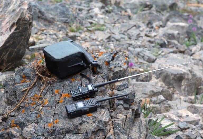 Two Land Mobile Radio handsets kept on a rock in hilly terrain.