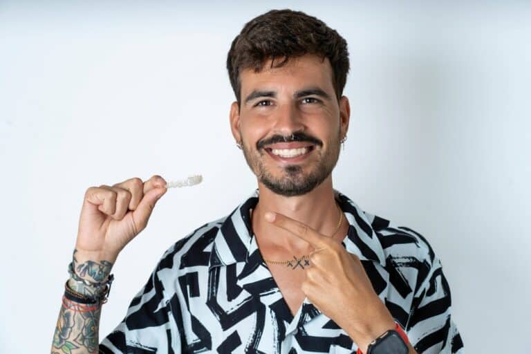 A smiling man shows off his clear aligner.